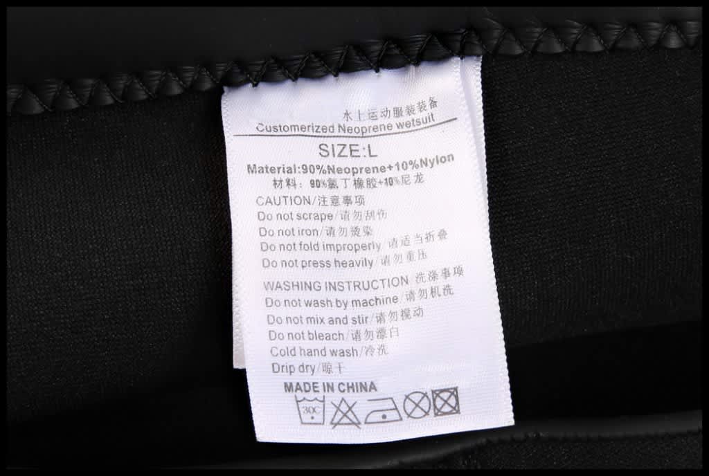 A close-up of a care label attached to neoprene shorts, featuring care instructions and material details.