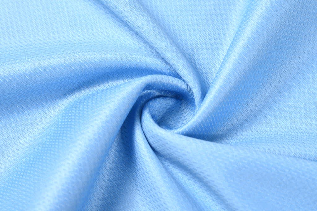 A piece of light blue fabric with a textured surface, arranged in a spiral pattern.
