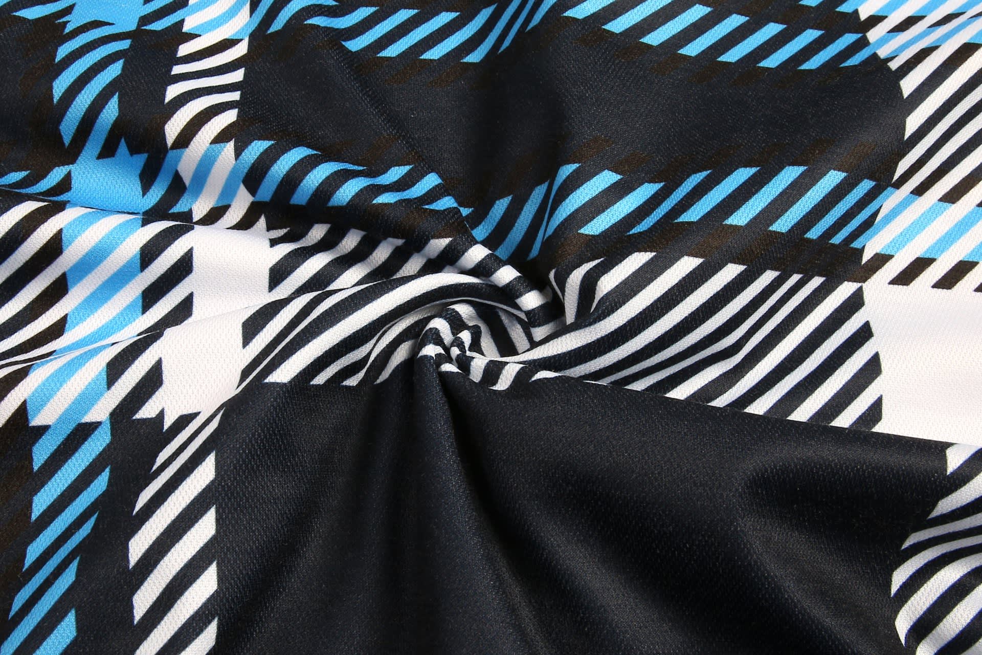 A fabric featuring a blue, black, and white checkered pattern in a swirling arrangement.