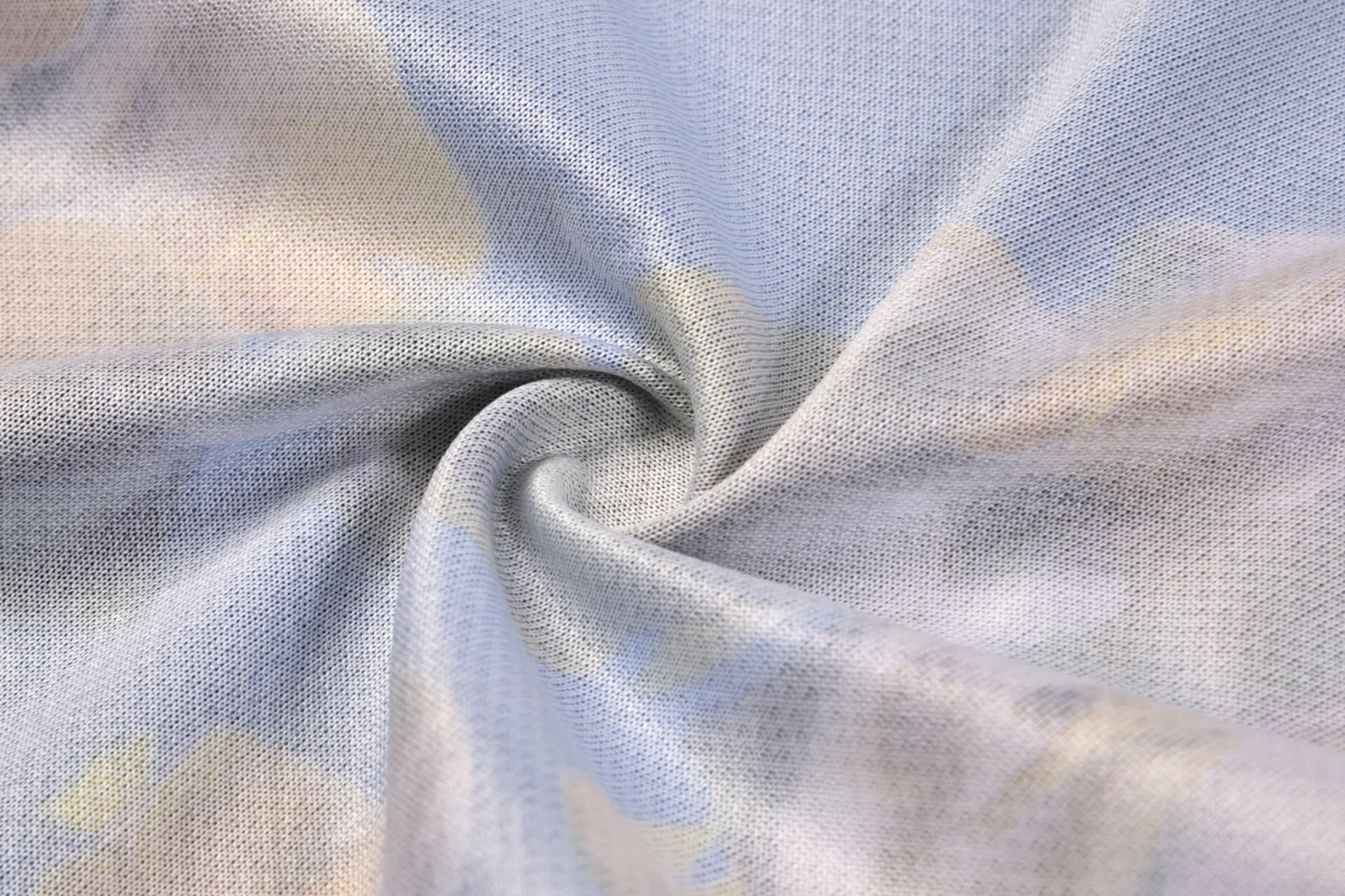 A fabric swirl featuring a light blue background with soft, abstract patterns in pastel colours. It has a smooth texture.