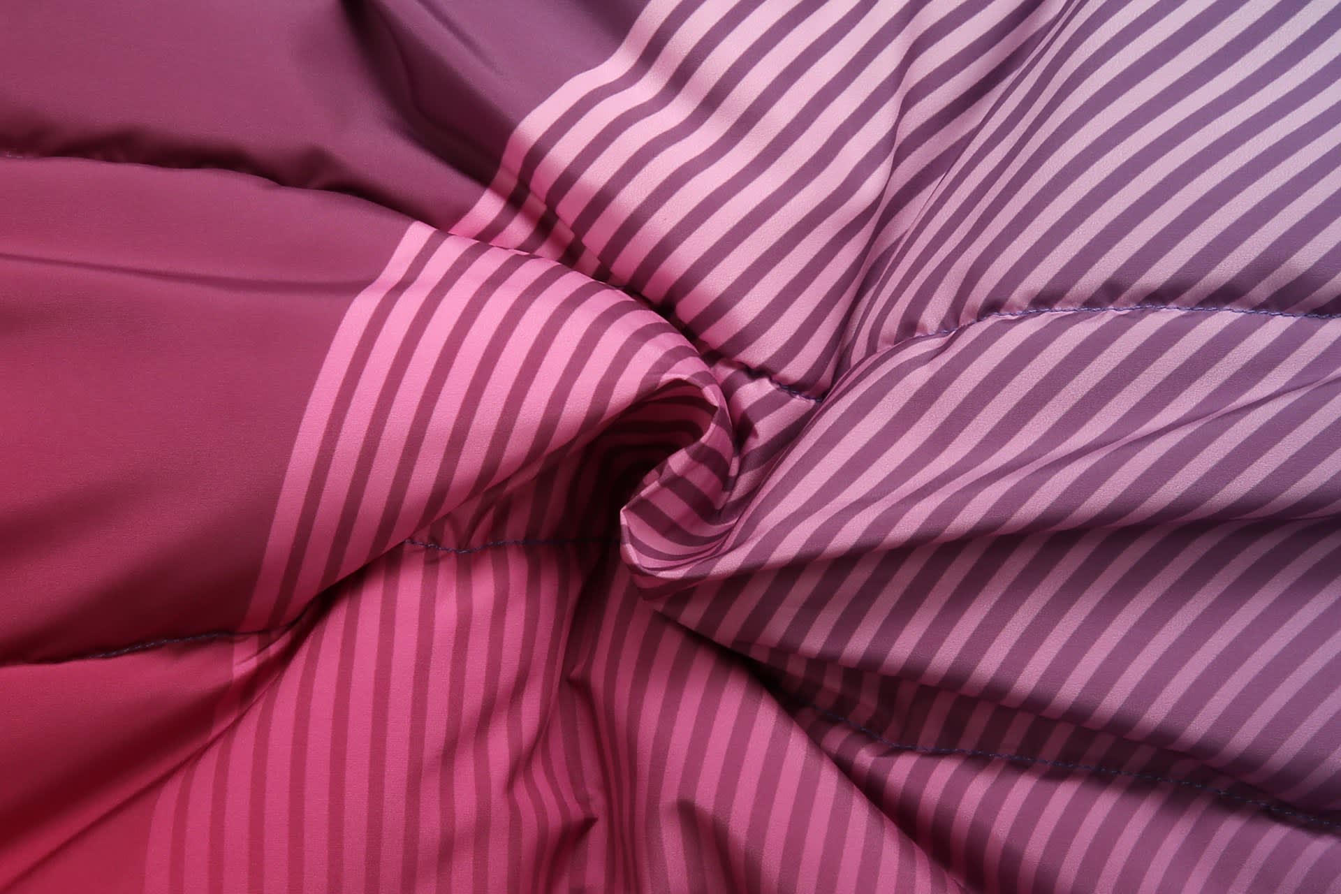 A textured fabric featuring gradients of pink and purple stripes, showcasing the material of a winter coat.