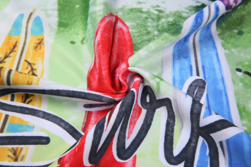 A close-up of a colourful fabric featuring surf-themed designs in greens, reds, and blues with a logo.