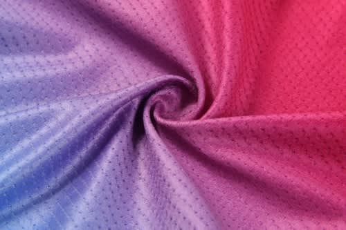 A swirl of fabric in gradient hues of pink and purple, featuring a textured pattern.