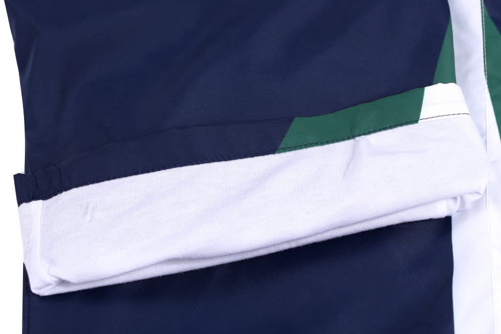A close-up of a navy fishing uniform with green and white accents, featuring a pocket and logo.