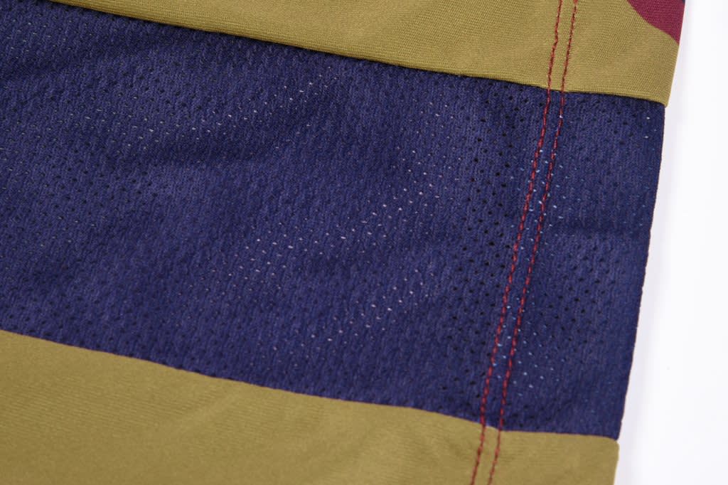 A PANEL SINGLET featuring a combination of olive green, navy blue, and red colours, with a textured mesh design.