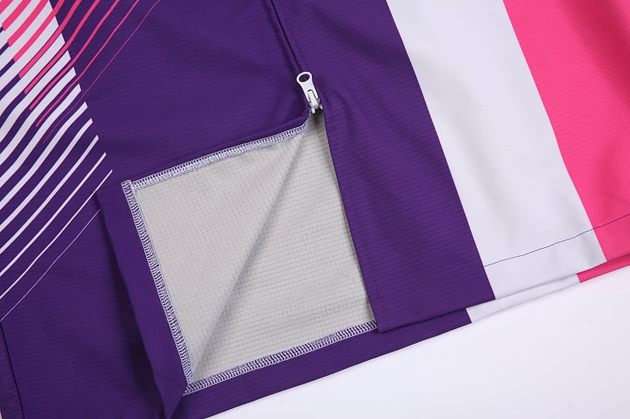 A section of a purple, pink, and white SOFTSHELL DECK COAT featuring a zippered pocket.