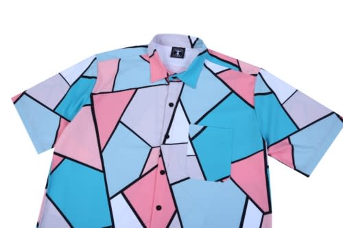 A short-sleeved shirt featuring a geometric pattern in shades of blue, pink, and white, with a pocket on the front.