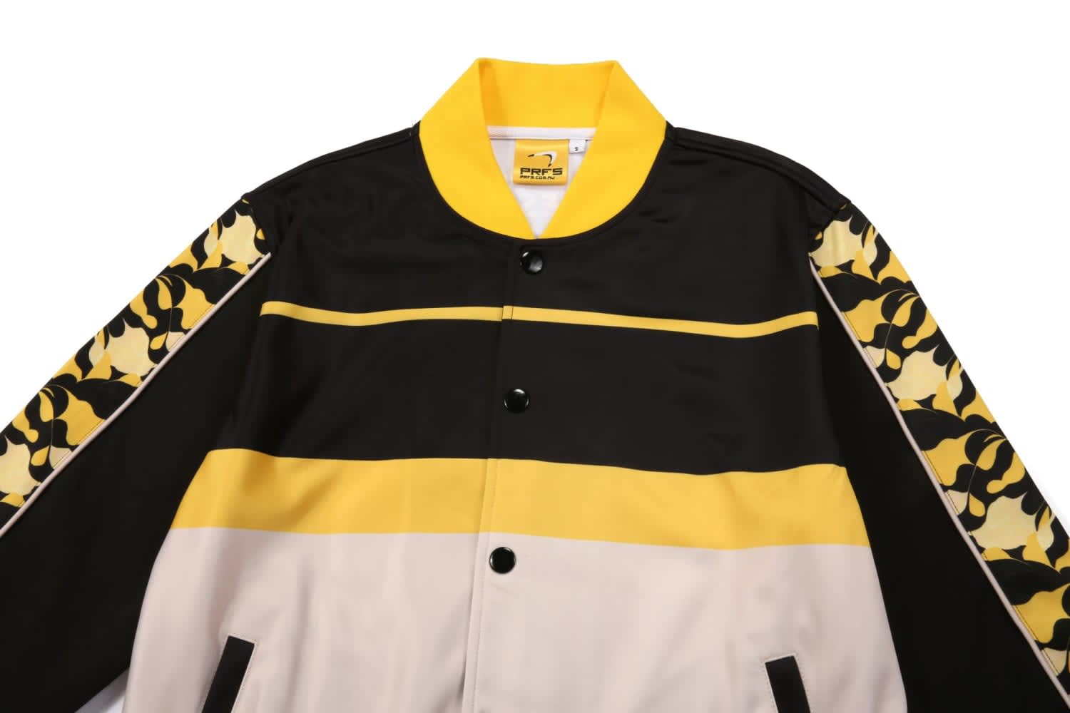 A multi-coloured jacket featuring black, white, and yellow stripes, with patterned sleeves and a logo.