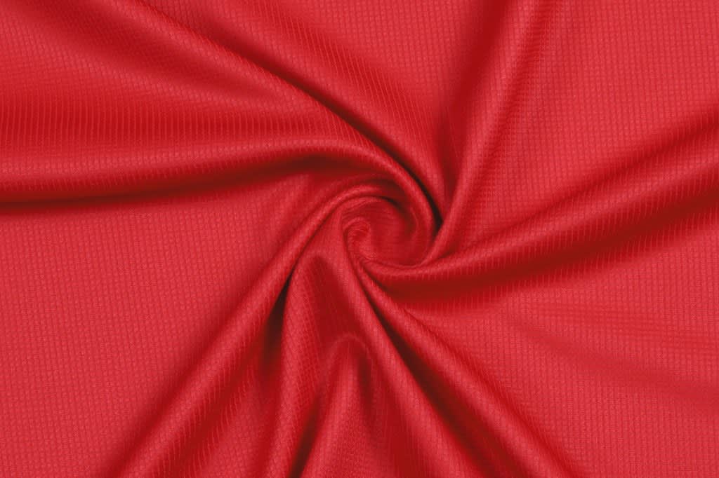 A vibrant red fabric with a textured surface, arranged in a spiral pattern.