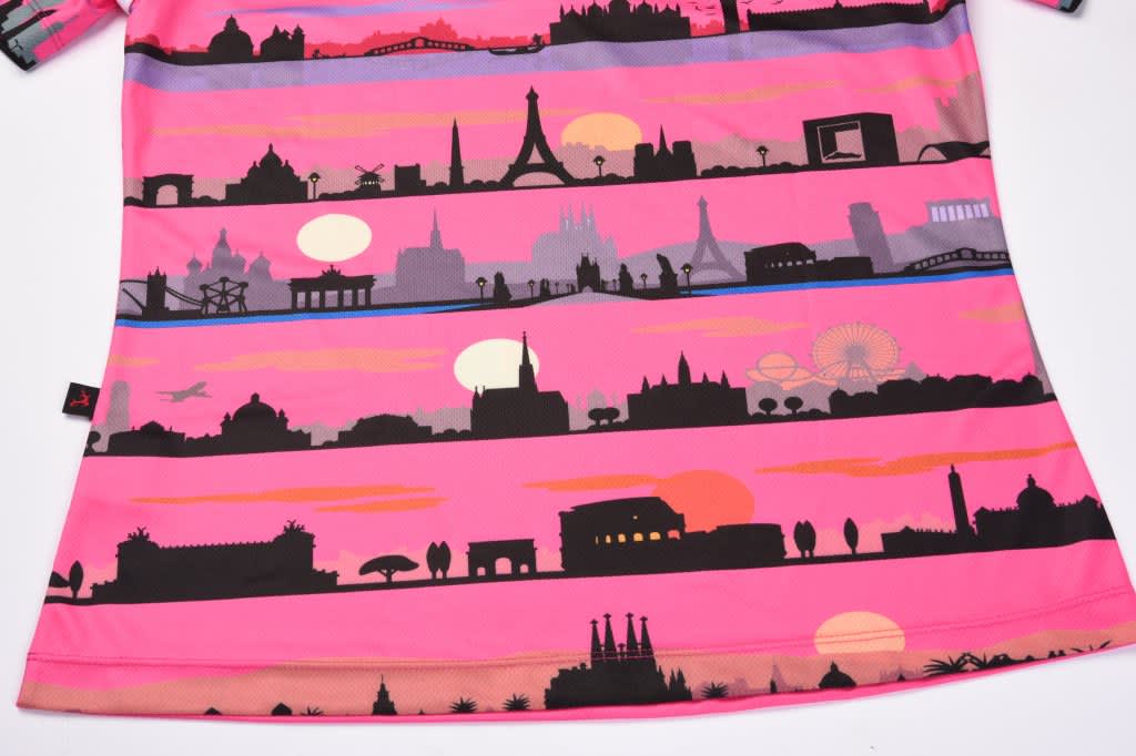 A pink sublimated polo featuring a skyline design with silhouettes of famous landmarks against a sunset background.