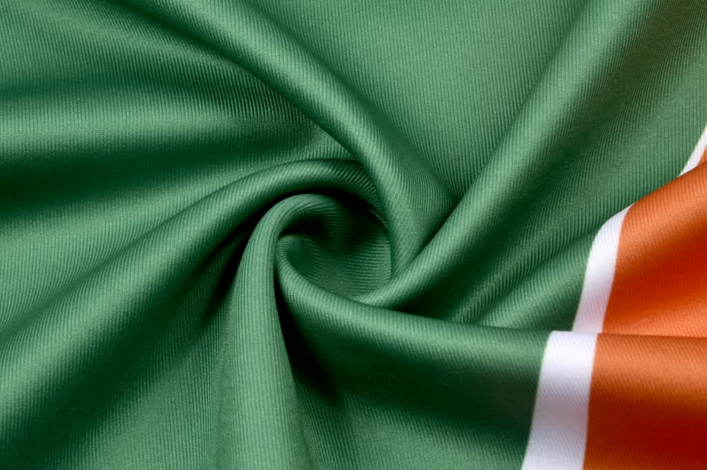 A smooth, green fabric with orange and white stripes, featuring a logo or branding.