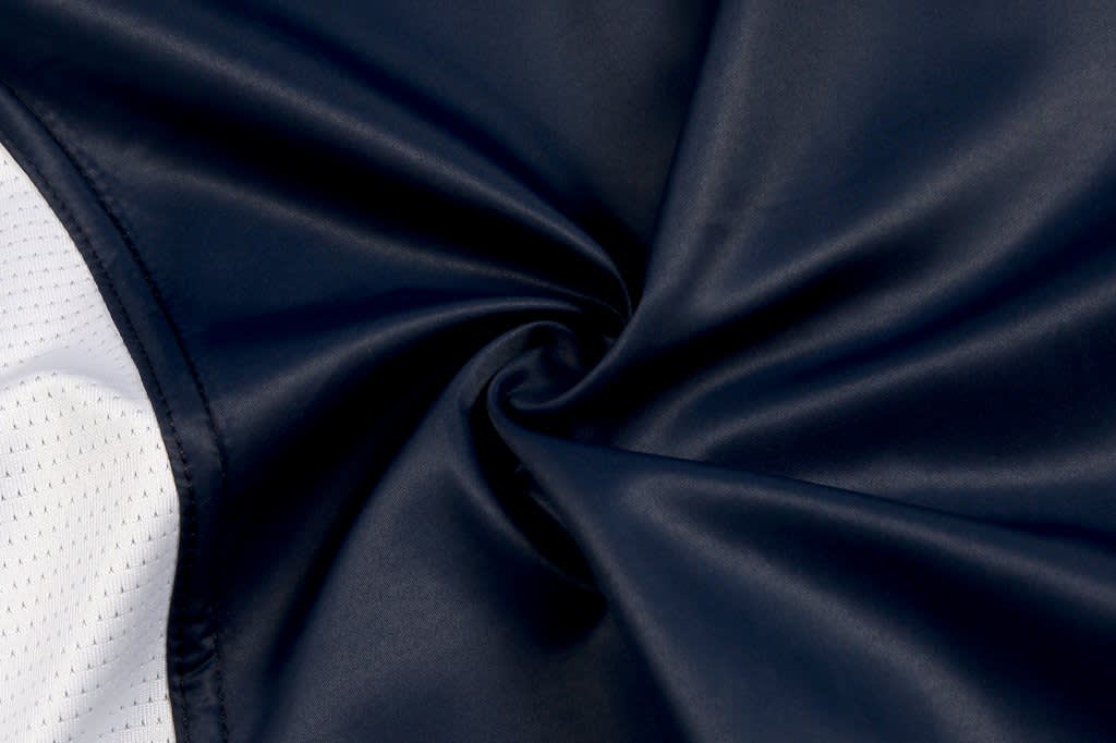 A waterproof woven vest in navy blue with a smooth, shiny texture and a contrasting white panel.