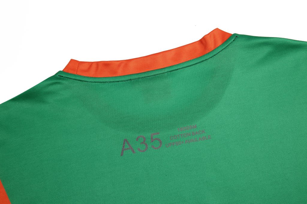 A green custom made T-shirt featuring an orange collar and a branding logo on the back.