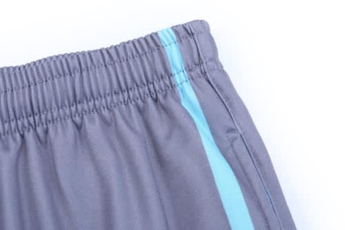 Grey training zip pants featuring light blue side stripes and an elastic waistband. Includes a logo.