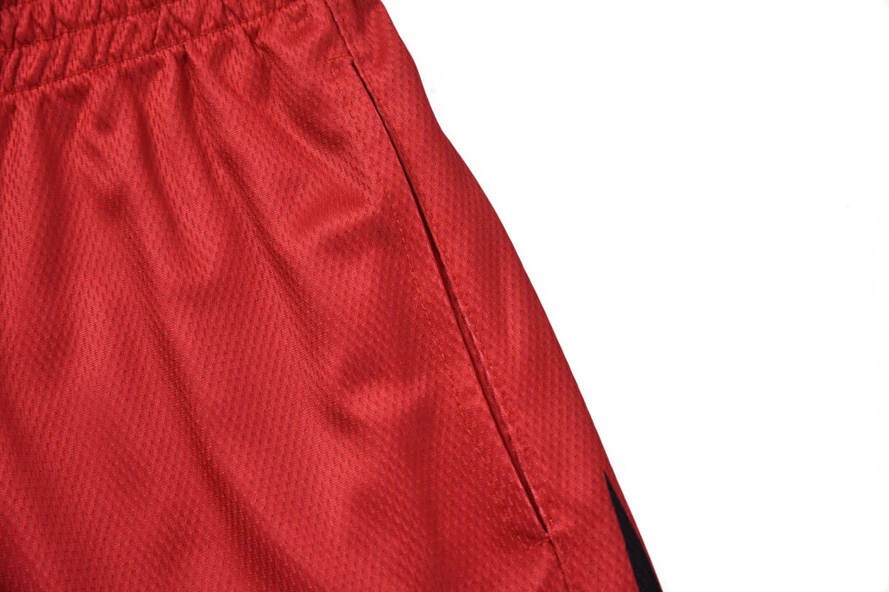 Red tracksuit bottoms with a side pocket detail and a black accent. Features an unspecified logo.