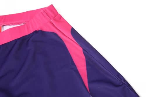 A pair of sports shorts in navy blue and pink with a branded logo on the side.
