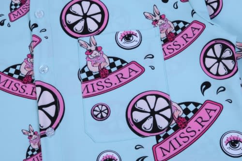 A light blue shirt featuring a playful pattern with pink accents, including cartoon rabbits and graphic elements.