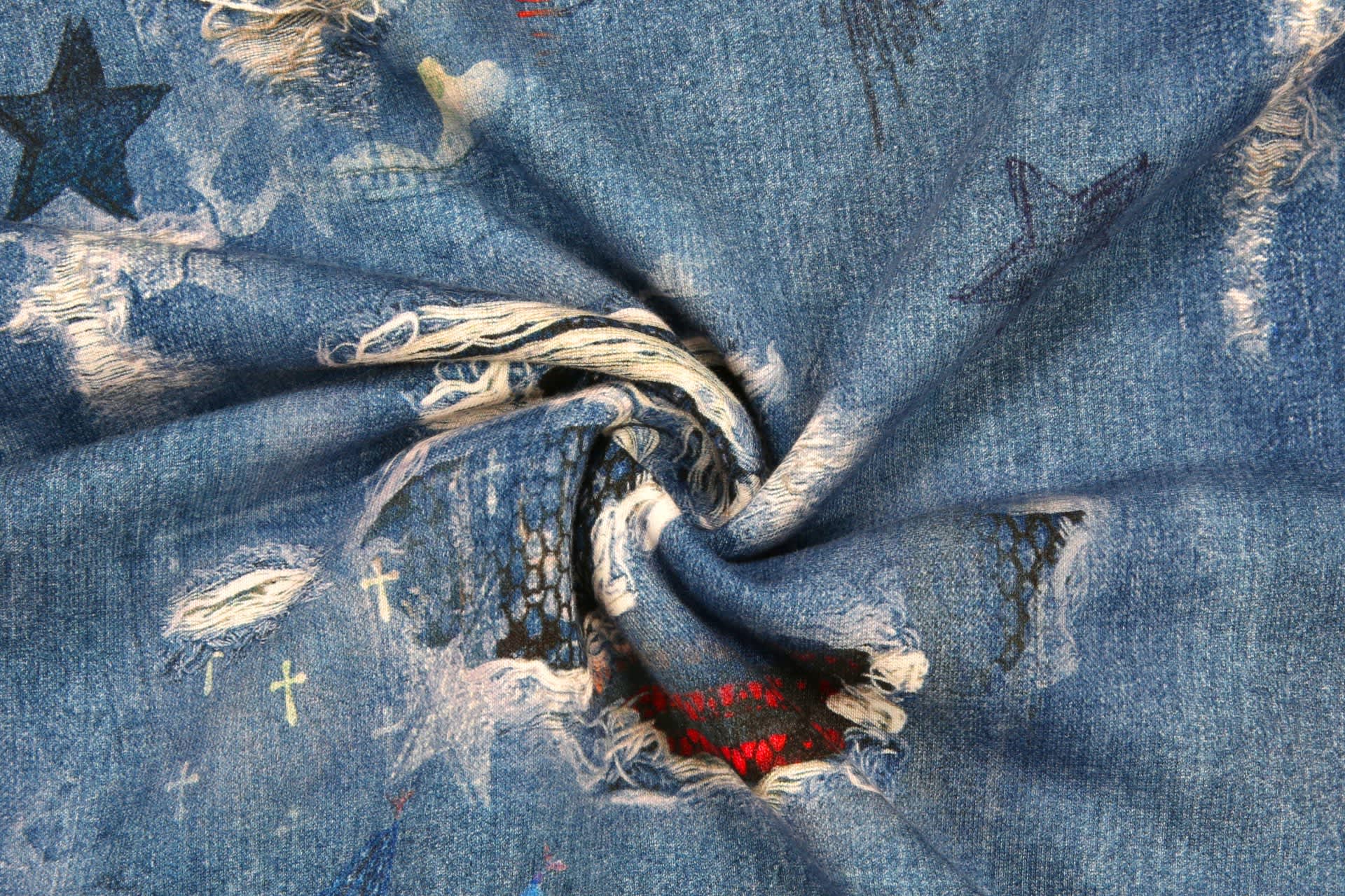 A close-up view of denim fabric featuring various coloured patches, stars, and distressed details.