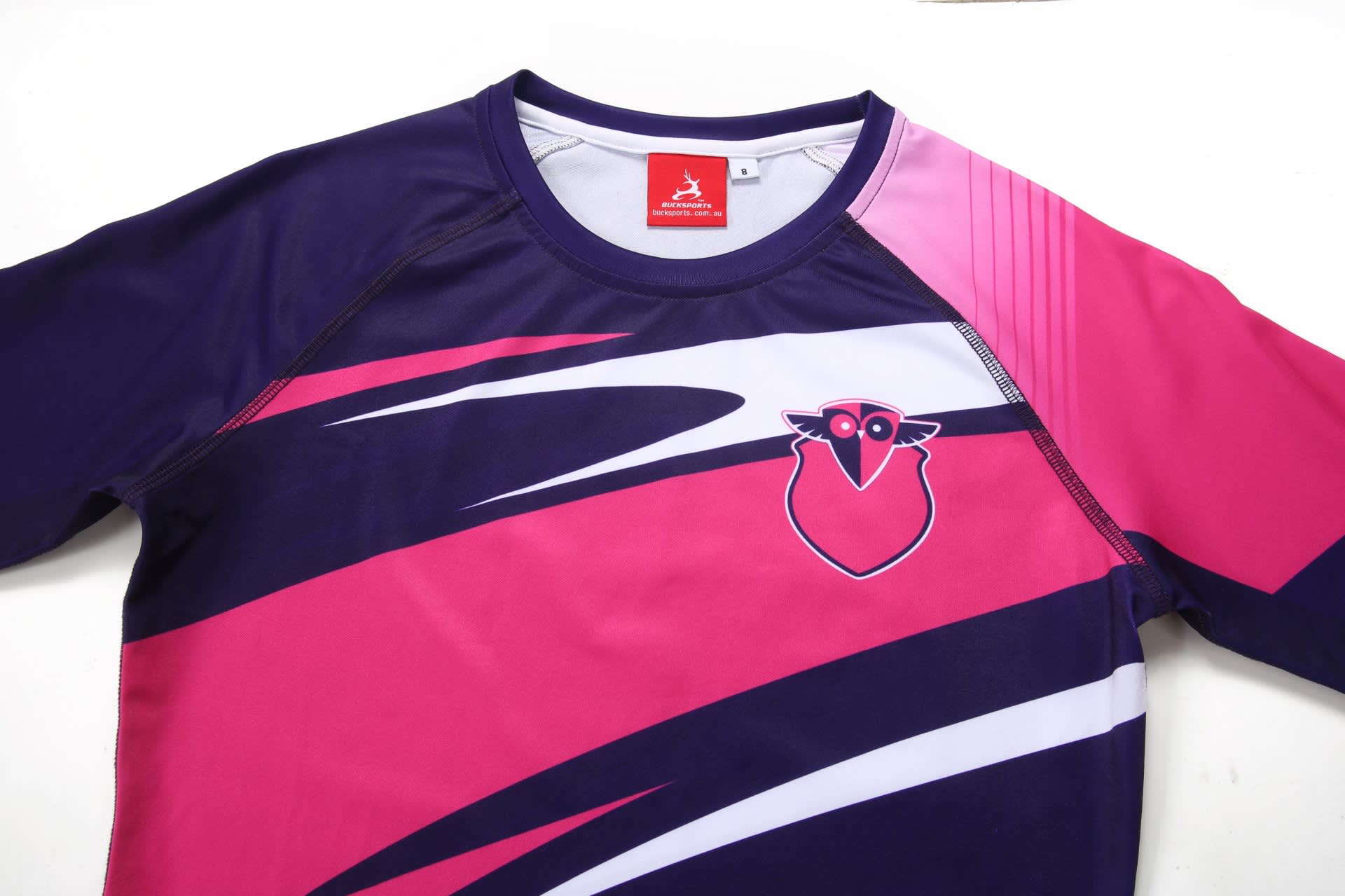 A pink and navy long-sleeve bathing suit featuring a logo, with a stylish wave design and contrasting colours.