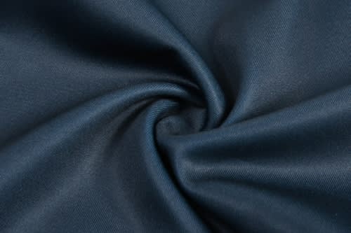 A close-up of dark navy blue fabric, showing a smooth, textured finish with a swirling pattern.