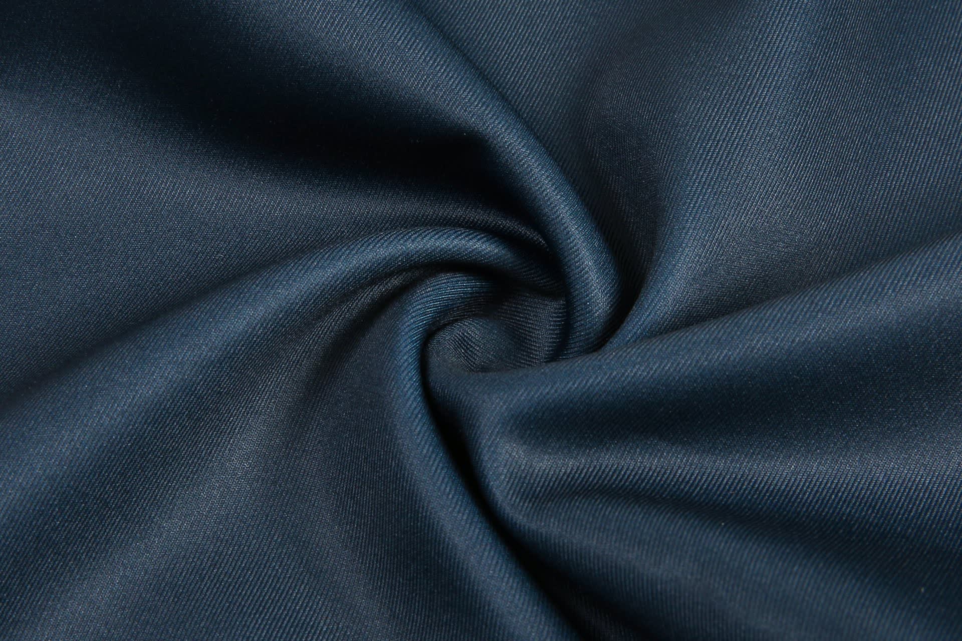 A close-up of dark blue fabric, showcasing a smooth texture with a swirling pattern.