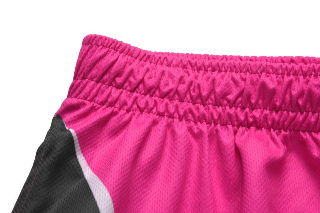A close-up of the waistband of pink sports pants featuring a black side panel and elasticised band.