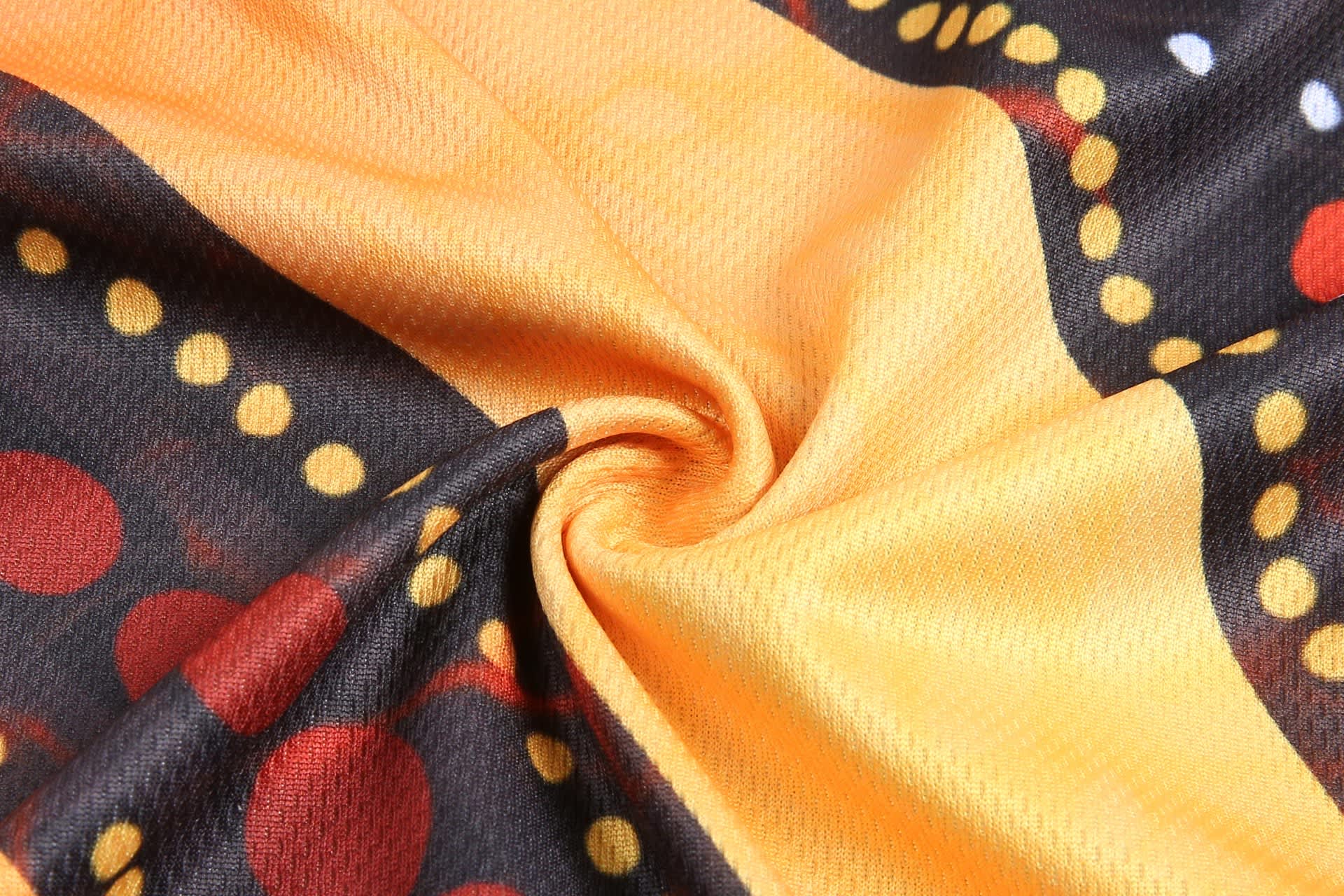 A fabric featuring a vibrant pattern with yellow, black, and red colours, showcasing an Aboriginal design.