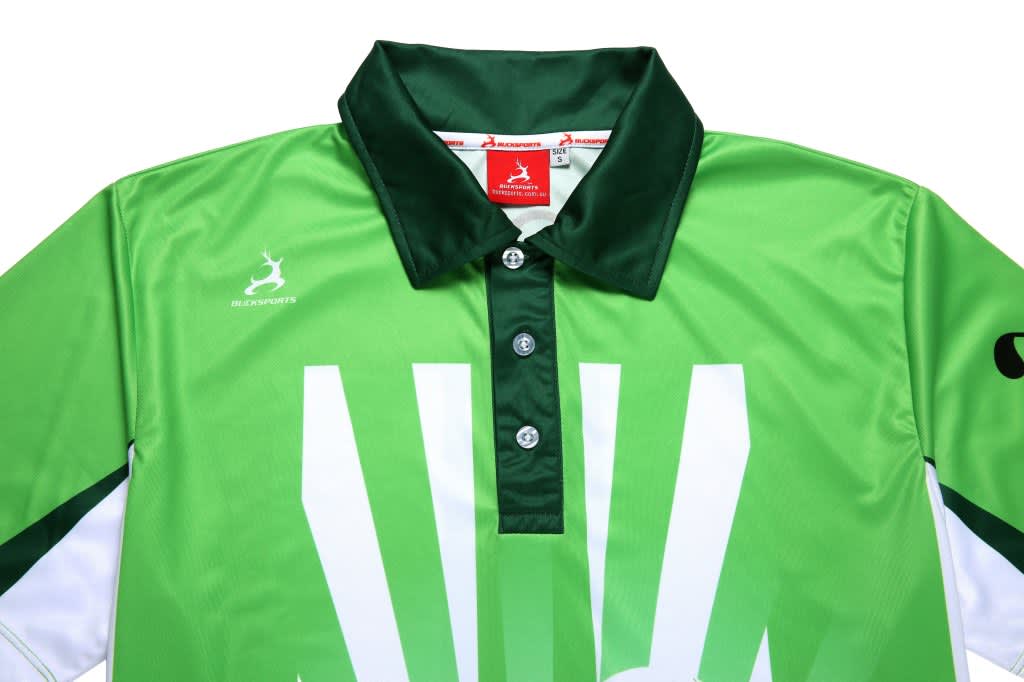 A green golf club shirt with a collar, featuring a logo and bold white graphic design elements.