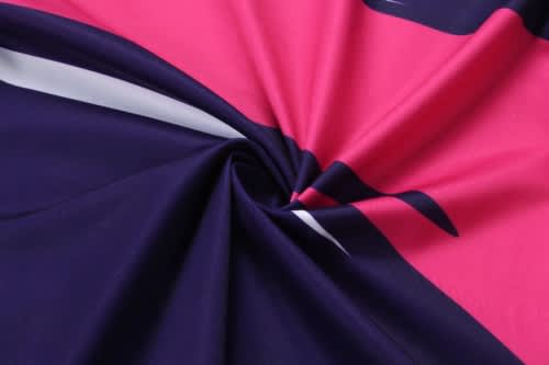 A close-up of a fabric featuring a design with navy, pink, and white colours, showcasing its smooth texture.