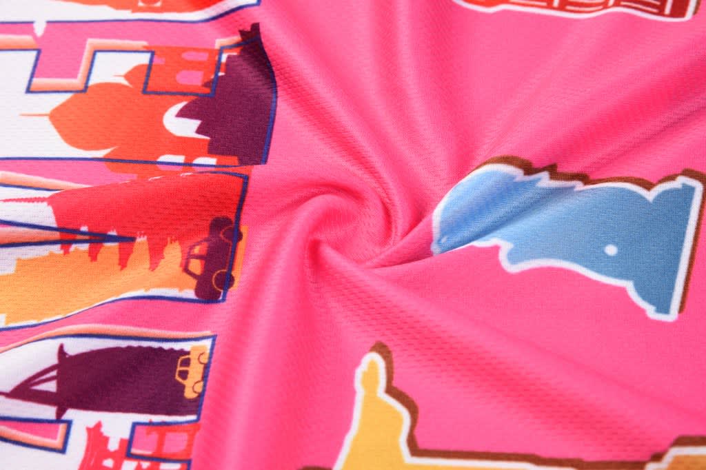 A vibrant pink polo shirt with a swirl pattern featuring colourful city silhouettes and landmarks.