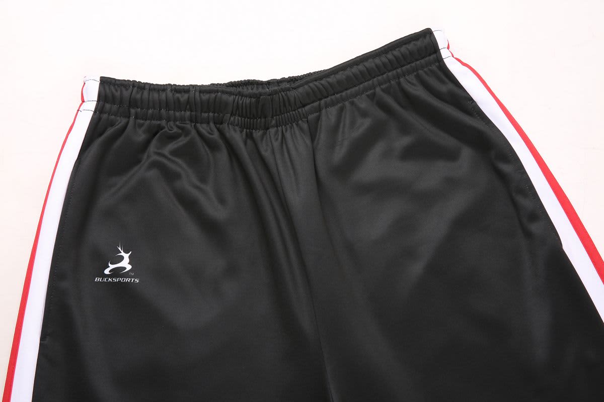 Black training pants with red side stripes and an emblem on the left side. Features an elastic waistband.