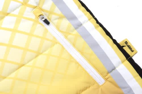 A close-up of a quilted coat with yellow and black sections, featuring a zip and a branding label.