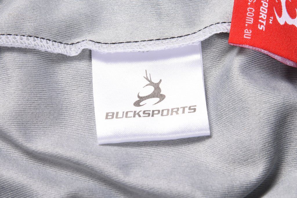 A grey sports jersey featuring a logo and a label indicating the brand.