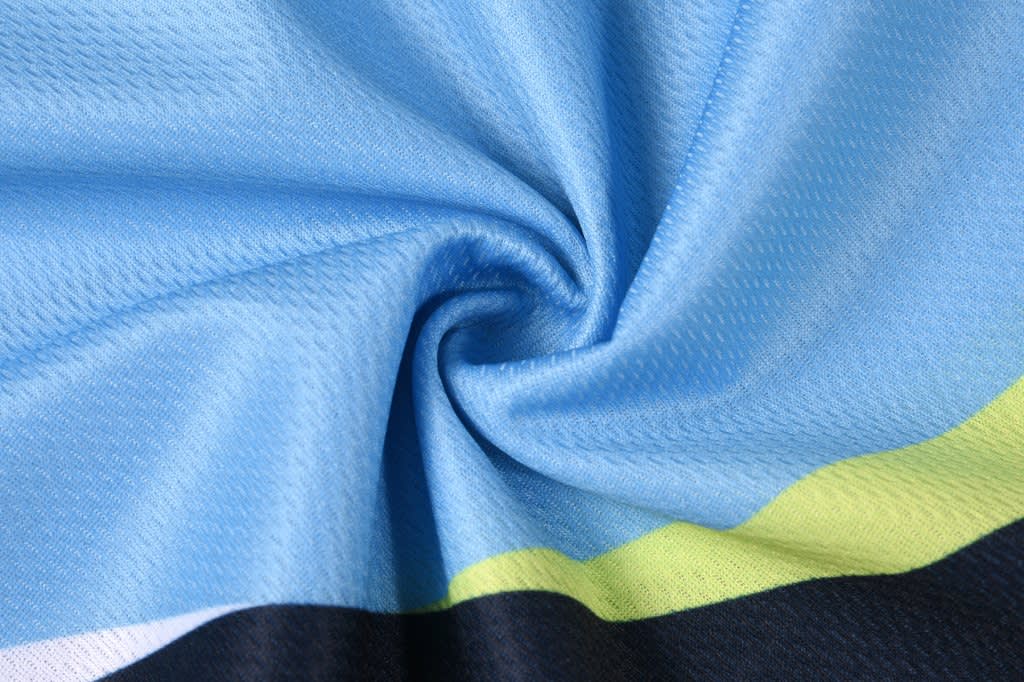 A blue and black fabric showcasing a textured pattern, with green accents visible in the design.