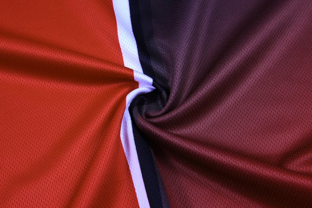 A close-up of a fabric featuring red, burgundy, and black colours with a white stripe, likely for a customised polo.