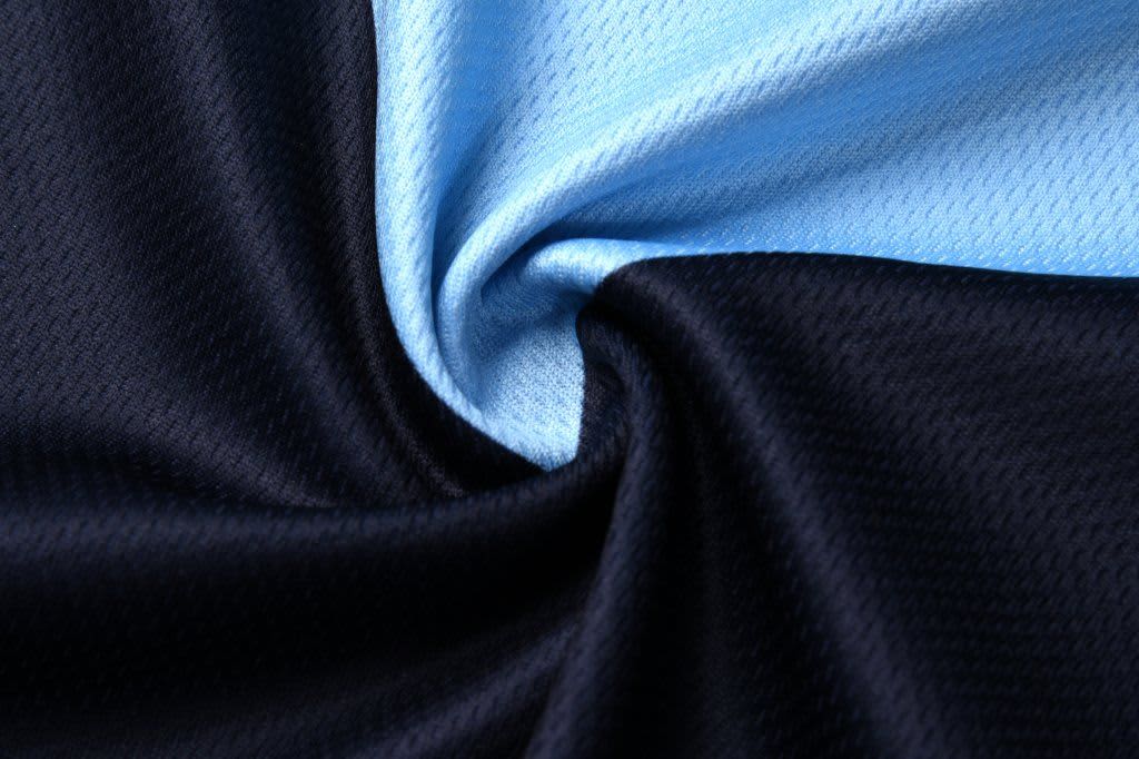 A singlet basketball top featuring a blend of light blue and black fabric with a textured pattern. It has a logo.