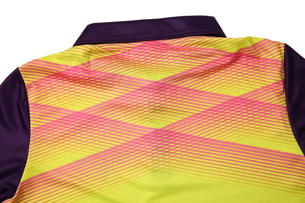 A fluorescent yellow polo shirt with purple sleeves and a geometric pink pattern on the back. It features a branding logo.
