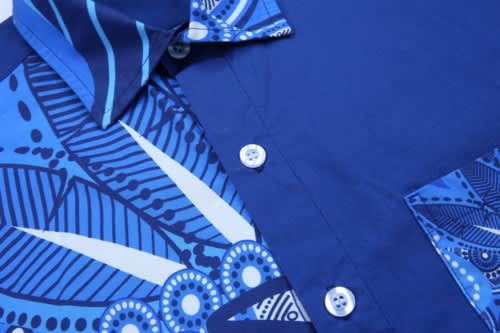 A blue shirt featuring a patterned design in various shades of blue, with buttons and a collar. It has a brand logo.