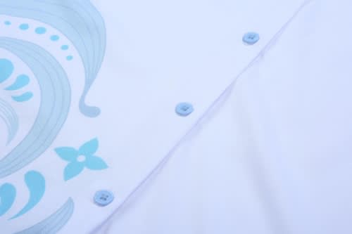 A white shirt featuring a blue floral design, with light blue buttons along the placket.