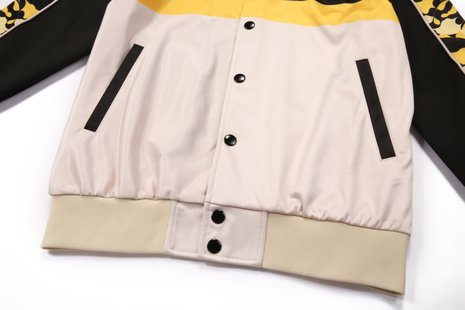 A multi-coloured jacket featuring black, yellow, and beige elements with a branded logo.