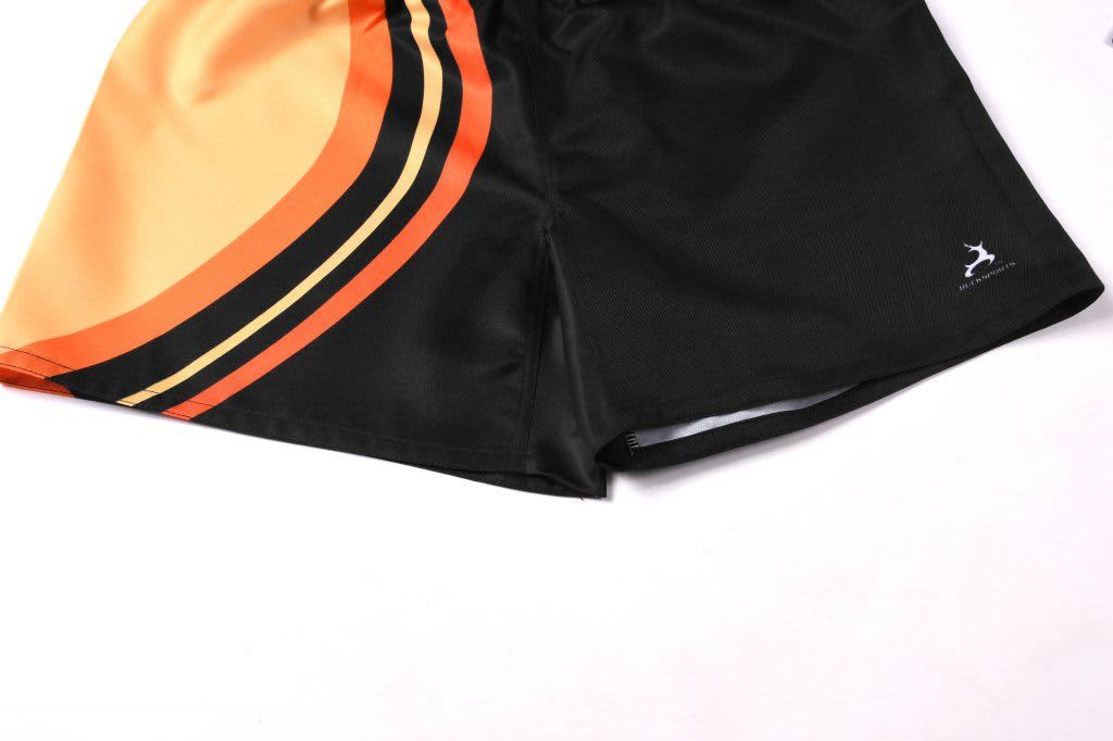 Twill shorts in black with orange and yellow detailing, featuring a logo on the side.