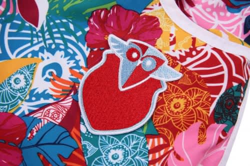 A vibrant women’s beach shirt featuring tropical patterns and a colourful owl logo.