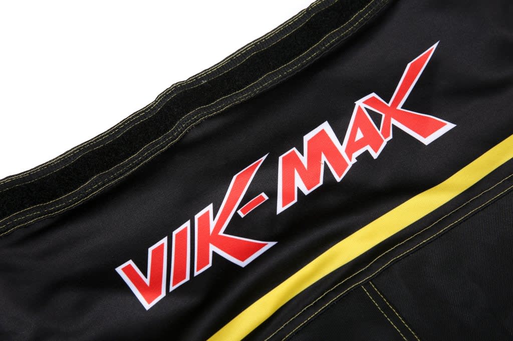 A pair of black ice hockey pants with yellow accents and a logo on the waistband.