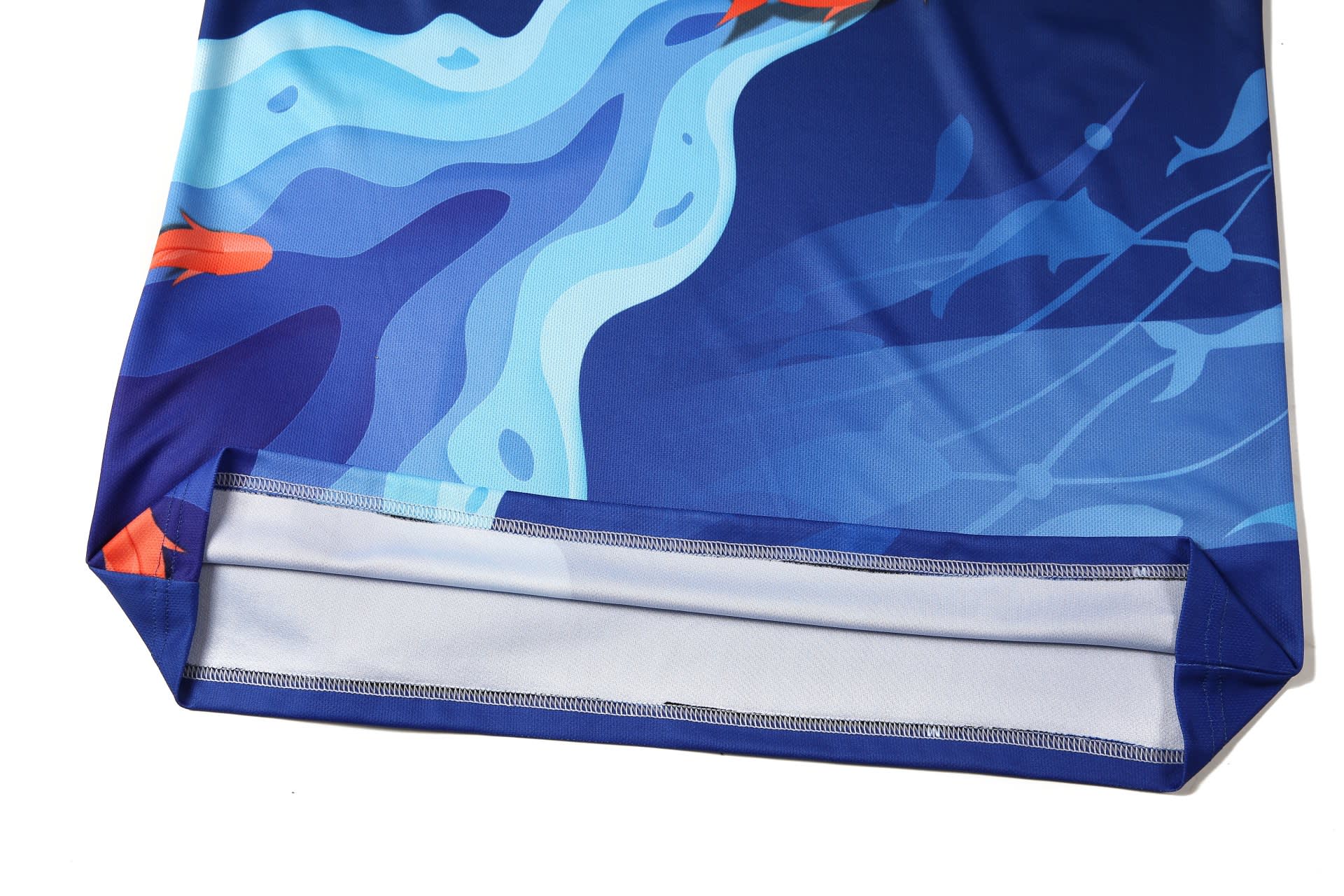 A blue sports jersey featuring a vibrant aquatic design with fish and waves. It includes a logo on the fabric.