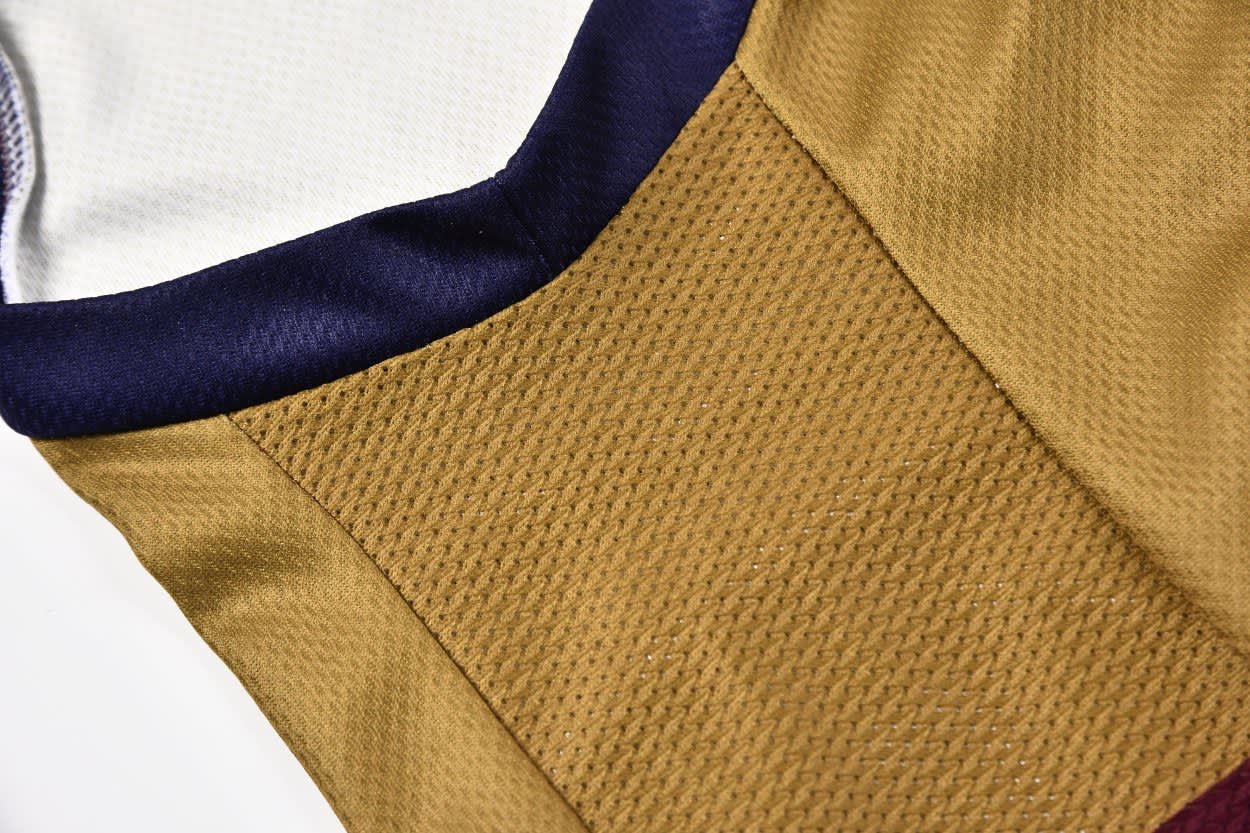 A singlet featuring a gold mesh panel with navy and white accents, showcasing a textured fabric design.