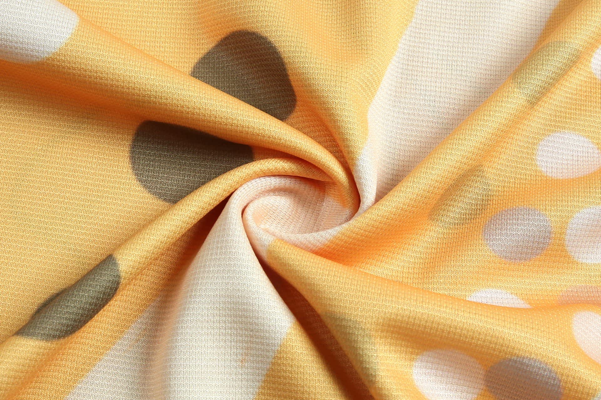 An orange fabric featuring abstract patterns with grey and white dots, showing a soft, textured surface.
