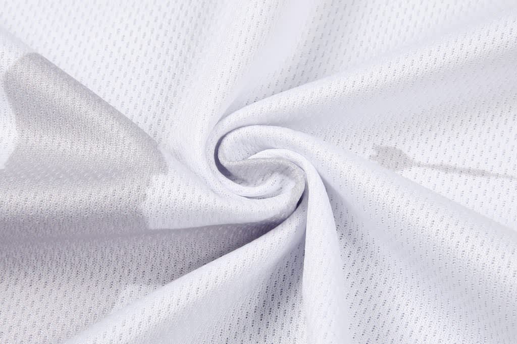 A soft, white mesh fabric with a subtle pattern, ideal for clothing. The material has a slight sheen.