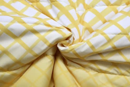 A yellow and white checkered fabric featuring a puffer design, suitable for winter coats with removable sleeves and hood.