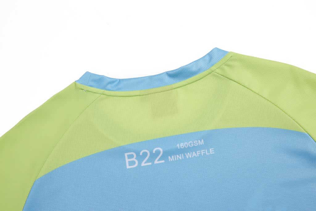 A sailing club t-shirt in green and blue with a branding logo on the back.