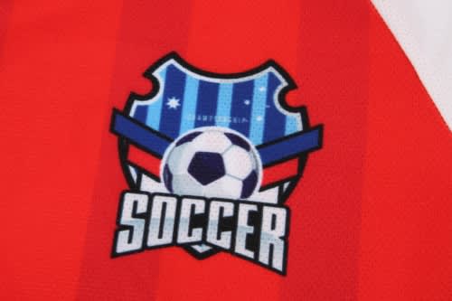 A vibrant red soccer jersey featuring a shield logo with a soccer ball and blue stripes.